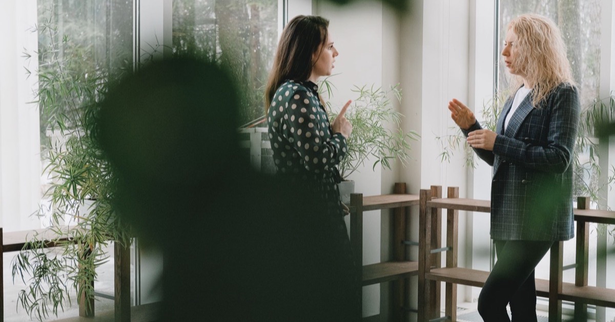 Duas profissionais conversando sobre atendimento em ambiente de trabalho