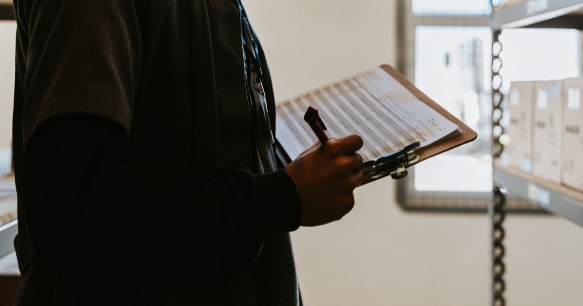 Profissional conferindo itens em prancheta durante levantamento