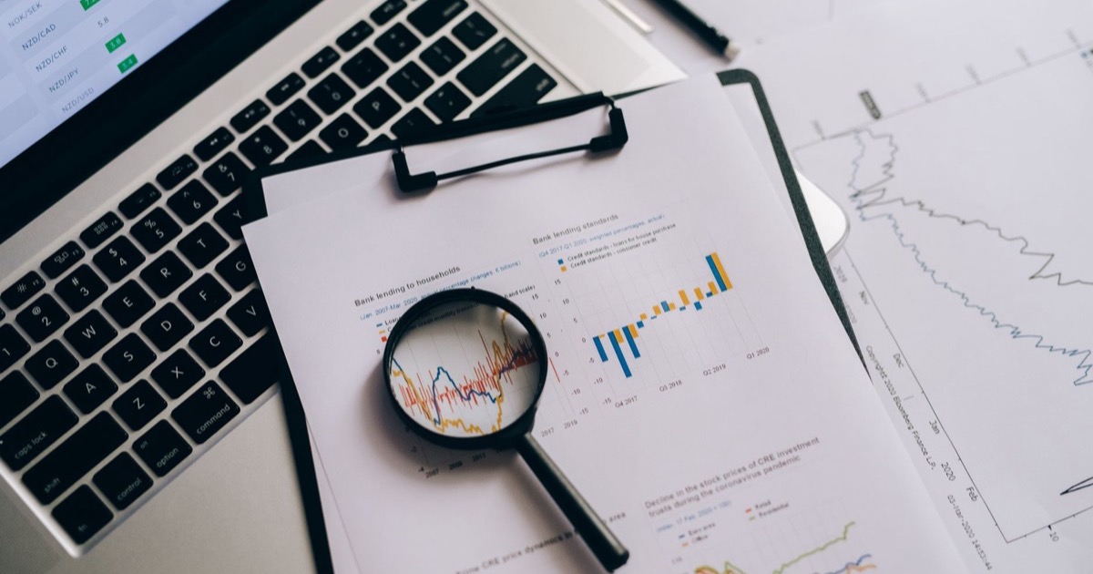 Relatórios técnicos sendo analisados com lupa sobre a mesa